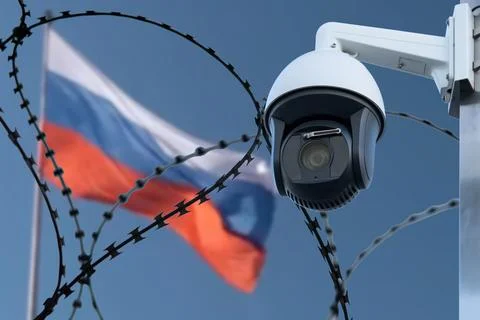 Barbed wire with a security camera on the background of the flag of Russia. Stock Photos