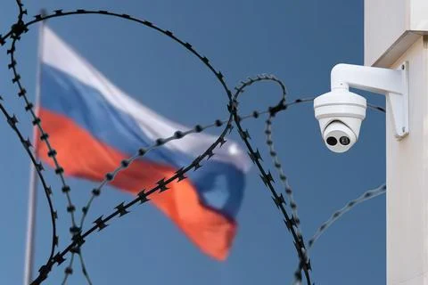 Barbed wire with a security camera on the background of the flag of Russia. Stock Photos