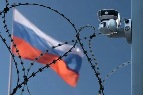 Barbed wire with a security camera on the background of the flag of Russia. Stock Photos