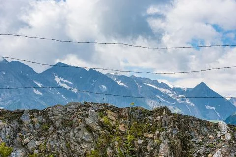 Barbed wire separating the mountain landscape in Alps Stock Photos