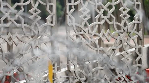 Barbed wire in spiral rows near a solid metal bar fence with Arabic pattern 스톡 사진