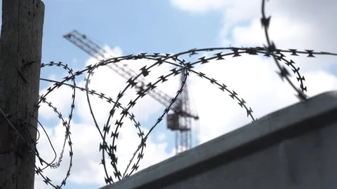 Barbed wire on the territory of the construction site. Crane on sky background Stock Footage 129793123