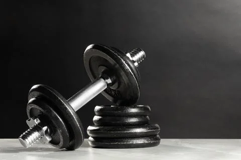 Barbell and stack of plates on light table against dark background. Space f.. Stock Photos