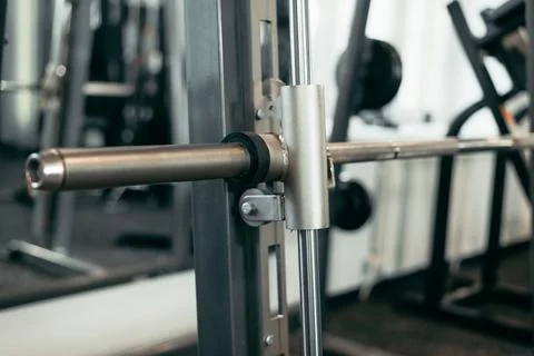 A barbell is resting on a squat rack in a gym environment. The space is equipped Stock Photos