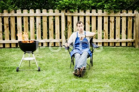 Barbeque: man checks time on watch Stock Photos