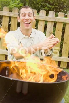 Barbeque: man excited by high bbq flames Stock Photos