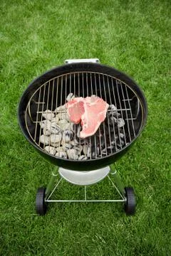 Barbeque: raw steak on grill Stock Photos