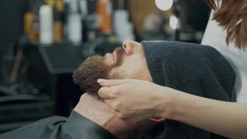 Barber Applying Lotion to Clients Beard Stock Footage 345586040