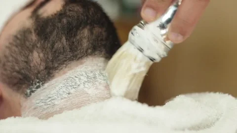 Barber applying shaving cream to man beard Stock Footage 80790662