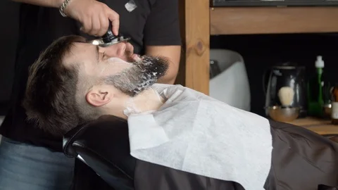 Barber applying shaving foam on beard of client Stock Footage 127177915