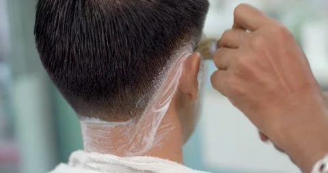 Barber applying shaving foam on beard of client.Male barber cuts customer's hair Stock Footage 241932451