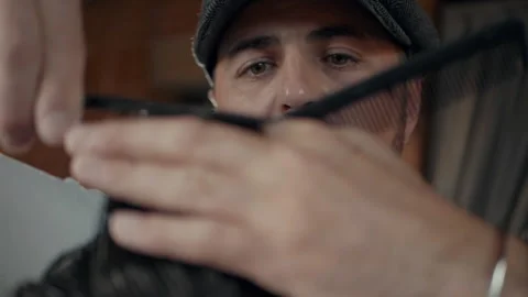 Barber with a beard and a cap. Barber makes a haircut with scissors. Stock Footage 132282863