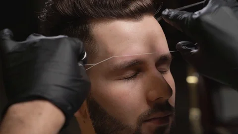 Barber in black gloves doing threading procedure for client Stock Footage 122833929
