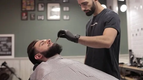 Barber combing beard of client at a barber shop. Stock Footage 70026540