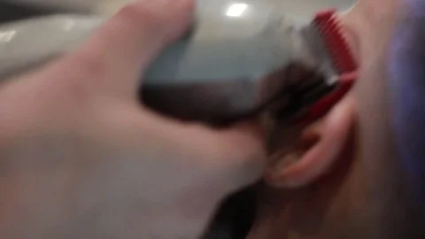 Barber cuts client’s beard with professional beard trimmer in barbershop Stock Footage 73566062