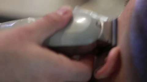 Barber cuts client’s beard with professional beard trimmer in barbershop Stock-Footage 73566076