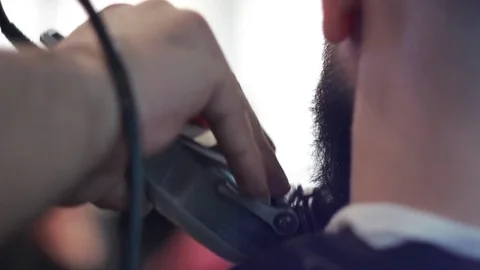 Barber cuts client’s beard with professional beard trimmer in barbershop Stock-Footage 73566080