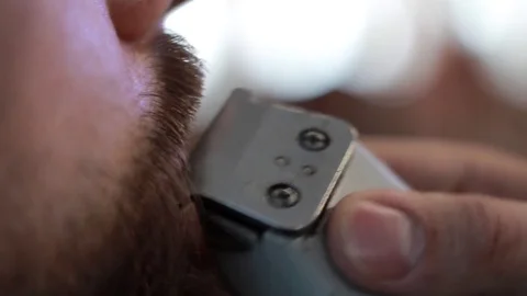 Barber cuts client’s beard with professional beard trimmer in barbershop Stock-Footage 73566122