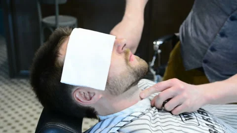 Barber cuts clients beard with a professional beard trimmer in a barbershop on Video stock 90465404