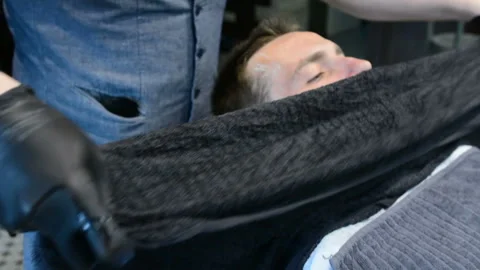 Barber cuts clients beard with a professional beard trimmer in a barbershop on Stock-Footage 90466356