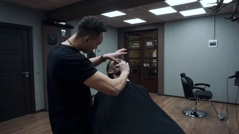 Barber cuts the customer's beard with a razor. Stock Footage 81531622