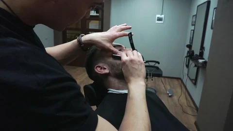 Barber cuts the customer's beard with a razor. Stock Footage 81531792
