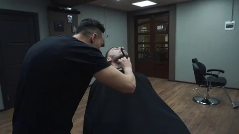 Barber cuts the customer's beard with a razor. Stock Footage 81531987