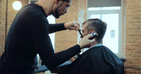 Barber cuts the hair of the client to the machine. Brutal men's hair salon. Stock-Footage 105437246