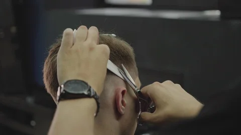 Barber cuts the hair of the client with scissors. Close up. Attractive male is Stock Footage 112606503