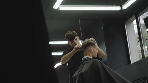 Barber cuts the hair of the client with scissors. Attractive male is getting a Video stock 112606537