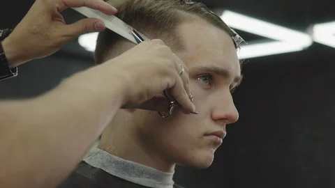 Barber cuts the hair of the client with scissors. Close up. Attractive male is Video stock 112831088