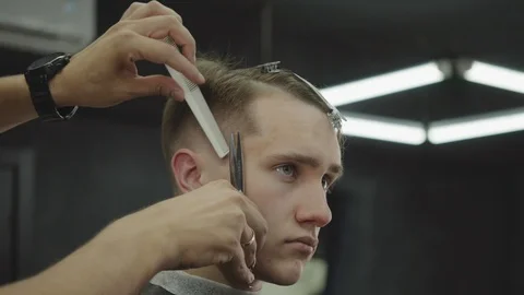 Barber cuts the hair of the client with scissors. Close up. Attractive male is Stock Footage 112831197