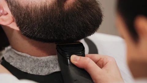 Barber cuts a man's beard with a typewriter in the salon Stock Footage 157621358