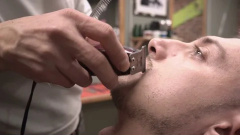 Barber cuts the mustache of the client with clipper haircuter close-up 4k. Stock Footage 81547799
