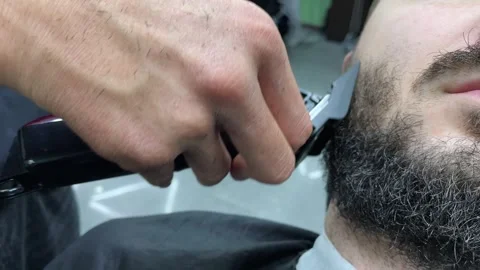 Barber cutting beard using electric trimmer, barber makes haircut for groom Stock Footage 242084045