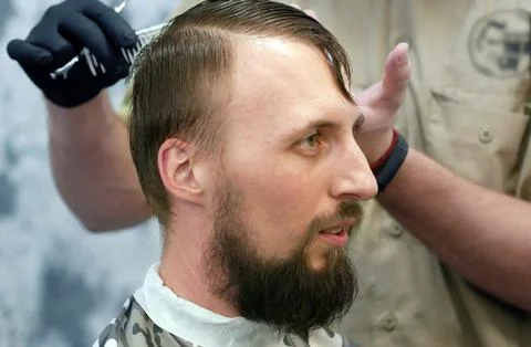 A barber is cutting a man with a beard Foto stock