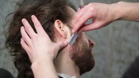 Barber is cutting man's beard with straight razor Stock-Footage 62979036