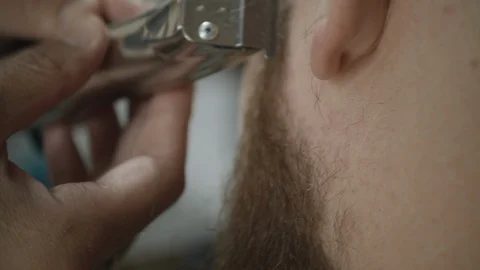 Barber cutting a man's beard with a trimmer. Video stock 117719255