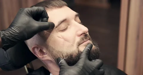 Barber doing threading procedure on face of man Stock Footage 158815953