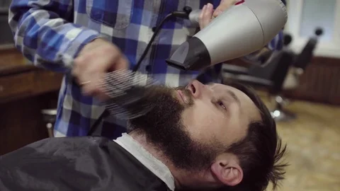 Barber is drying beard a bearded man with hairdryer in a barber shop Stock Footage 69987284