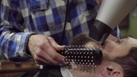 Barber is drying beard a bearded man with hairdryer in a barber shop Stock Footage 69987351