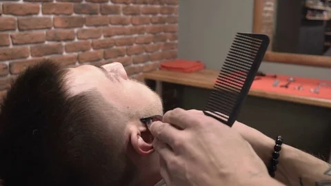 Barber forms customer whiskers using clipper haircuter close-up 4k. Stock Footage 81543881