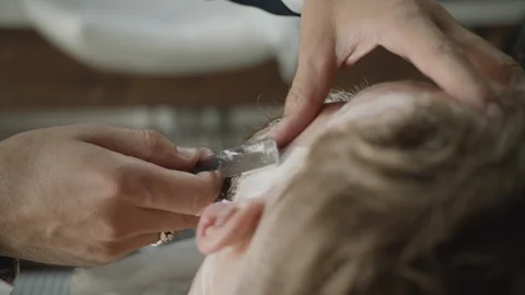 Barber gently cutting a man's beard with a razor Stock Footage 117712309