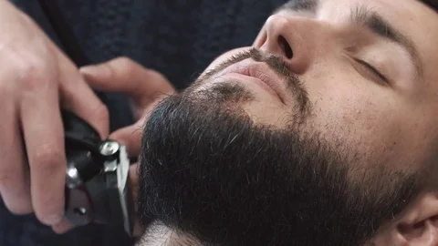 Barber hand cutting beard with clipper at barbershop. Closeup video, 4k. Barber Stock Footage 74560138