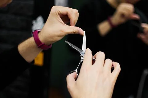 Barber holds sharp open scissors to do haircut in salon Stock Photos
