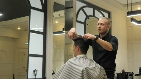 Barber is making haircut to his client. Indoors in the barber shop. Stock Footage 149703326