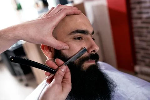 Barber a man with a beard in process of cutting Foto stock