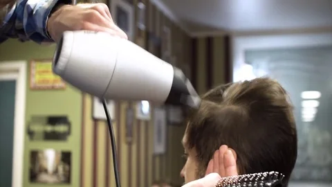 The Barber man in the process of drying a client's hair with a Hairdryer at the Stock Footage 69965326