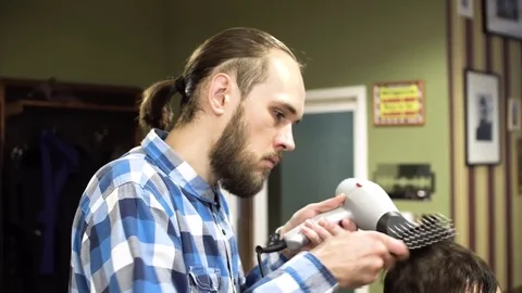 The Barber man in the process of drying a client's hair with a Hairdryer at the Stock Footage 69965626