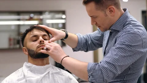 Barber master arranges a client's beard, massages the skin of the face Stock Footage 144453324